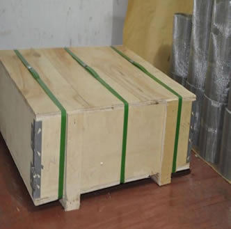 A wooden box on the floor and several rolls of unpacked wire mesh beside the box.