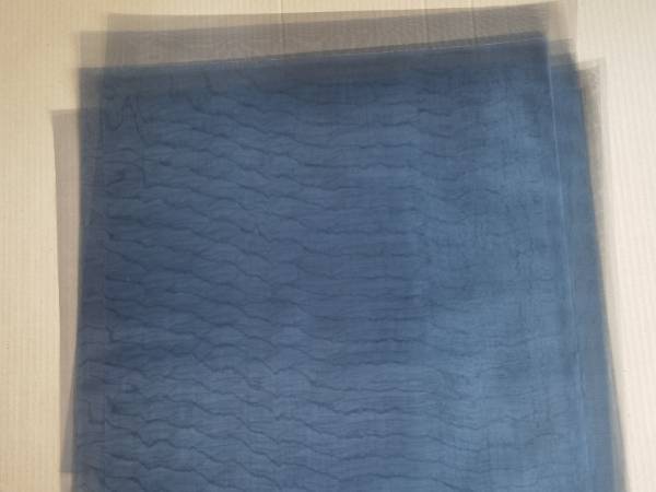 Cardboard holds multiple layers of square blackened stainless steel shielding mesh.