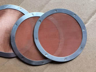 Three pieces of copper woven wire mesh filter discs on the paperboard.