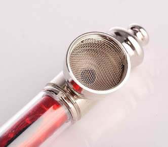 A red body metal pipe on the white background with a stainless steel filter disc in it.